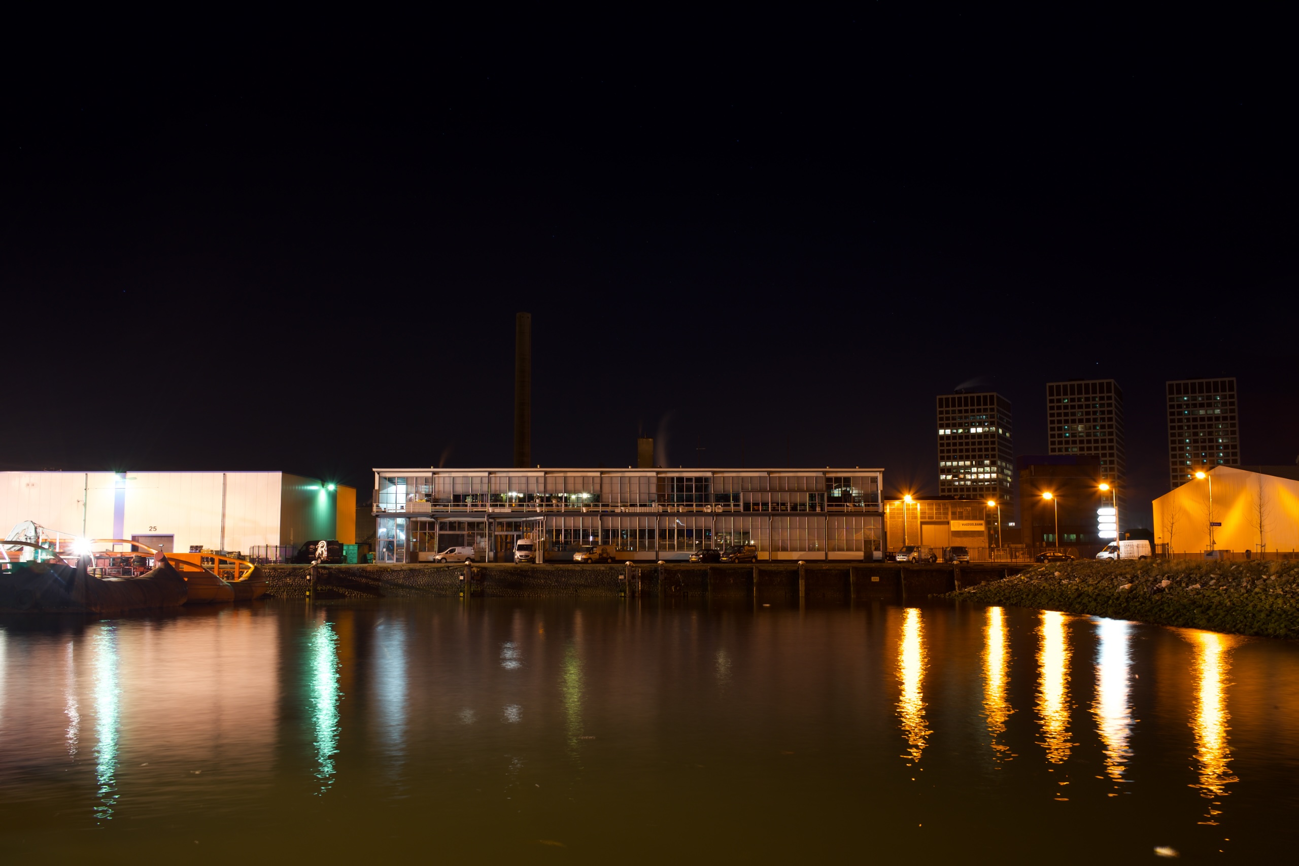 Vertrekhal Oranjelijn bij nacht, met oranje havenlichten weerspiegeld in de Lekhaven
